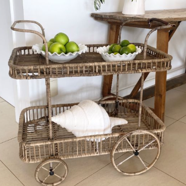Wicker cart with two bowls of limes and a white towel on a tiled floor.