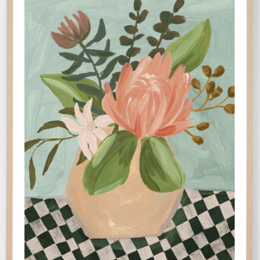 A framed art print featuring a still life painting of a pink protea flower in a beige vase, surrounded by green leaves, set against a light blue-green background with a black and white checkered surface.
