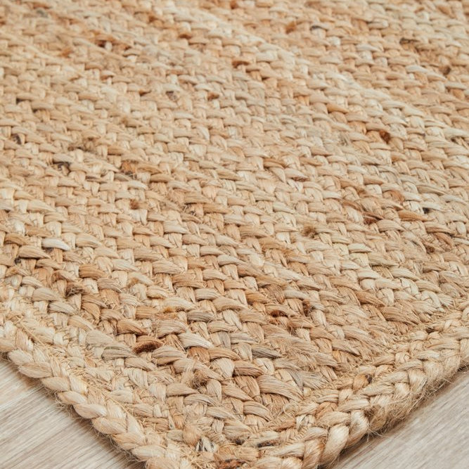 Close-up of a woven natural fiber rug on a wooden floor.