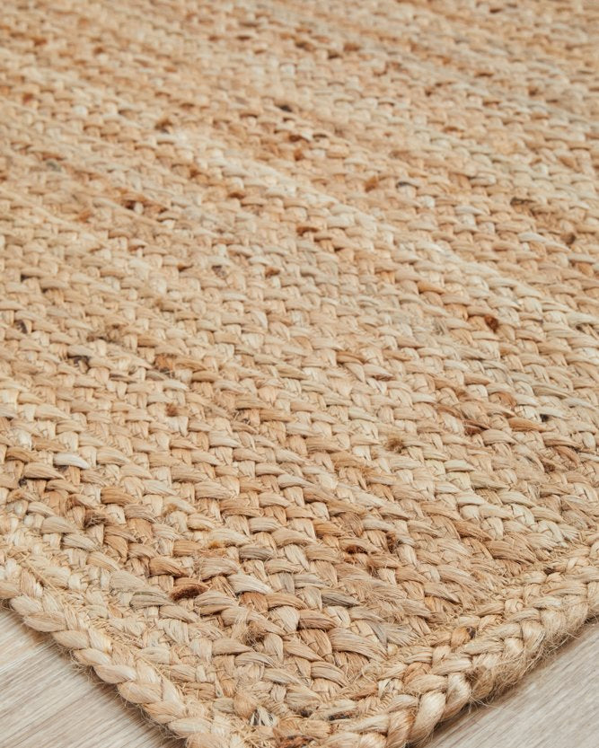 Close-up of a woven natural fiber rug on a wooden floor.