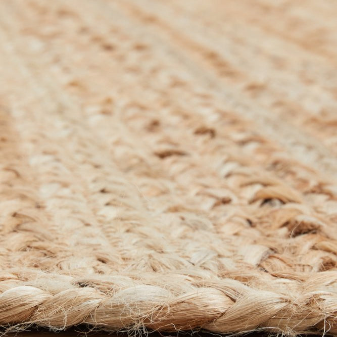Close-up of a woven natural fiber rug on a wooden floor.