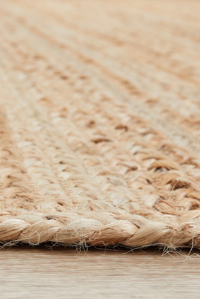 Close-up of a woven natural fiber rug on a wooden floor.