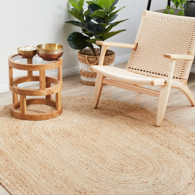 Round jute rug in a room with a wooden chair, small table, and potted plant.