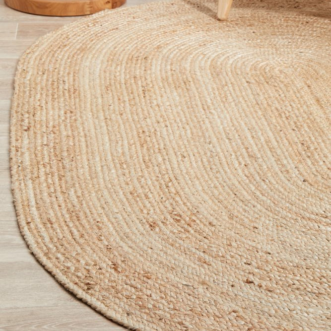 Round jute rug on a wooden floor with wooden furniture.