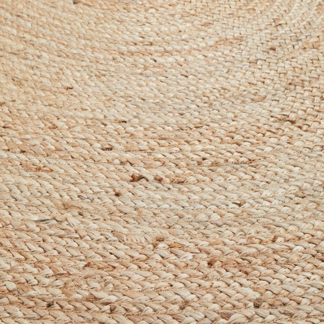 Close-up of a textured beige woven rug on a light wooden floor.