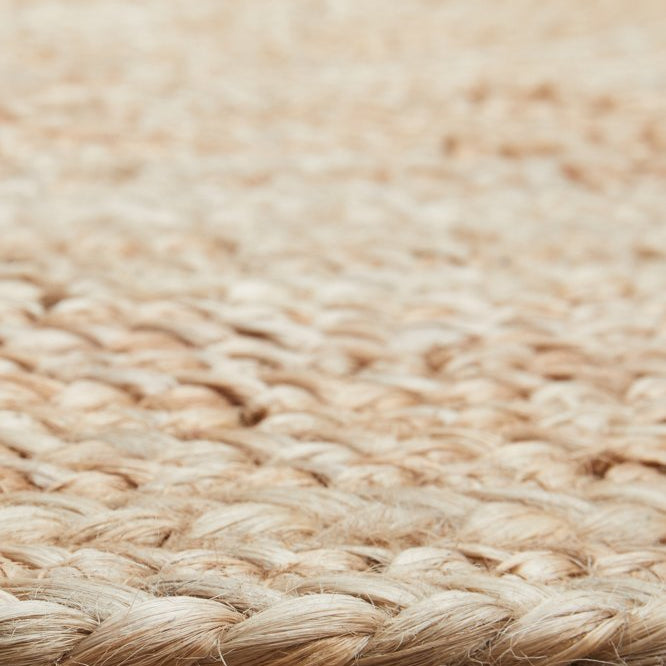 Close-up of a woven natural fiber rug on a wooden floor.