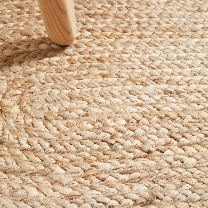 Close-up of a woven jute rug with a wooden chair leg.