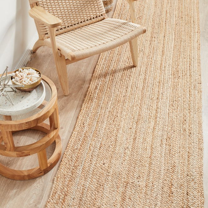 Woven natural rug on a wooden floor with a wicker chair and side table.