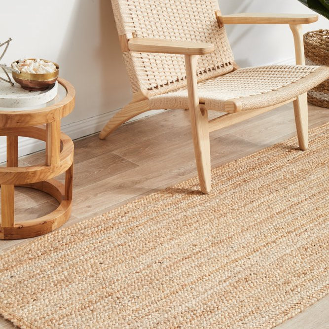 Woven chair and side table on a wooden floor with a jute rug.