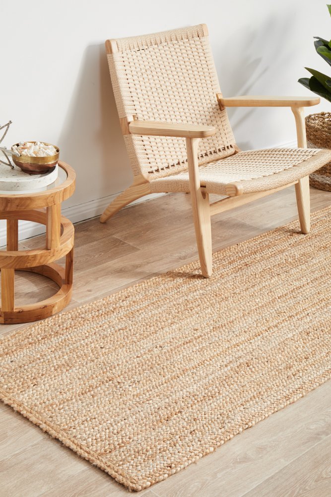 Woven chair and side table on a wooden floor with a jute rug.