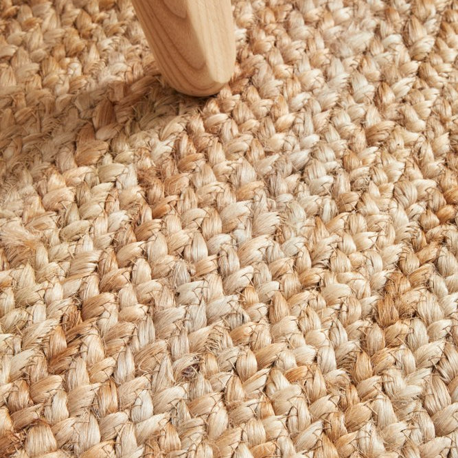 Close-up of textured beige carpet with a wooden furniture leg.