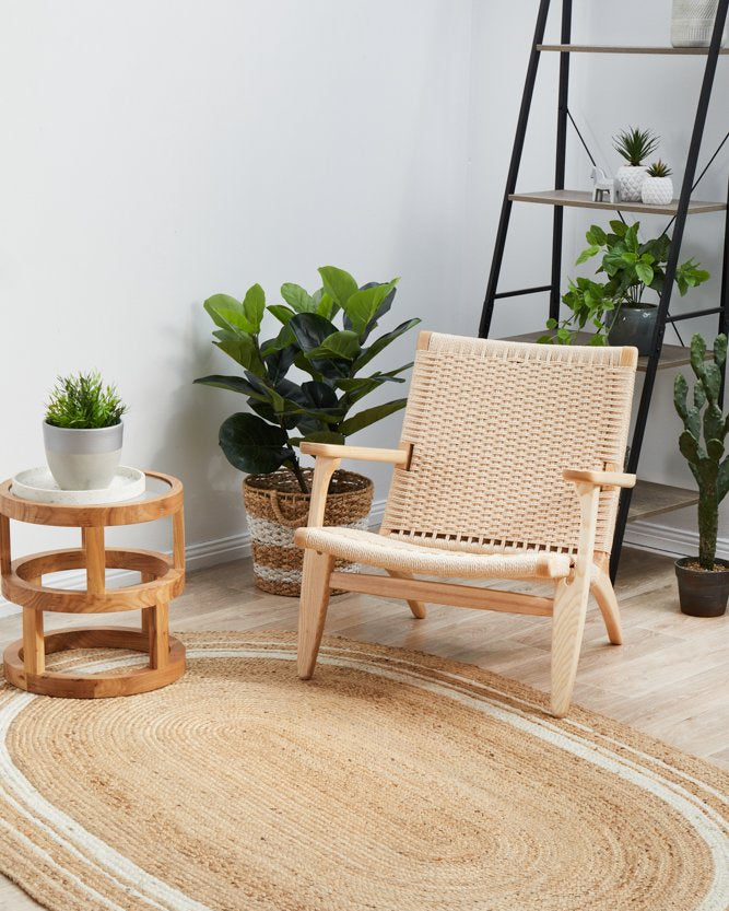Woven chair on a jute rug with plants and a ladder in the background