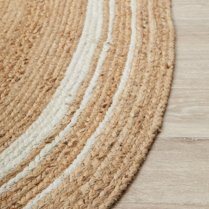 Round braided rug with beige and white stripes on a wooden floor