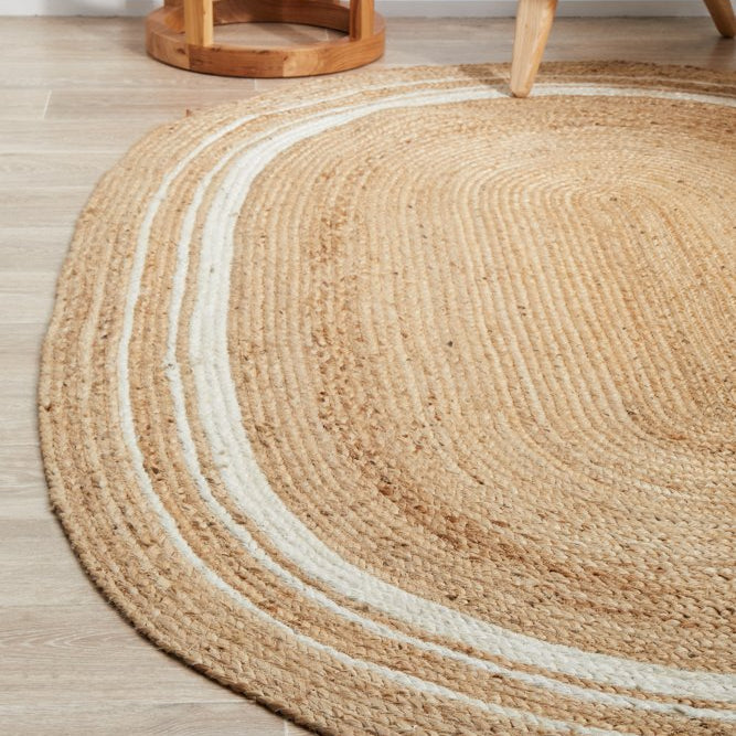 Round jute rug on a wooden floor with a chair and side table in the background.