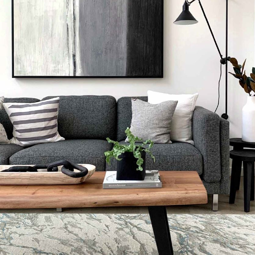 Modern living room with gray sofa, wooden coffee table, and abstract painting.