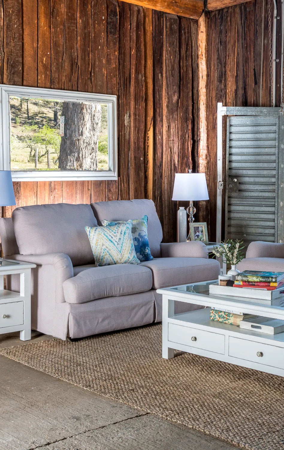 Living room with gray sofa, coffee table, and wooden walls.