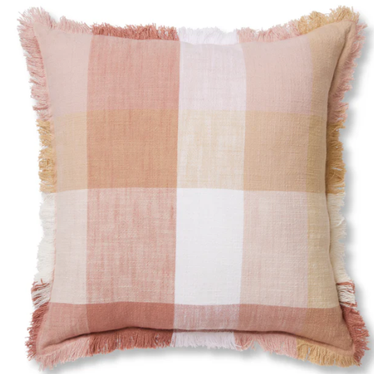 A square throw pillow with a soft plaid pattern in dusty pink, beige, white, and muted orange, finished with fringed edges.