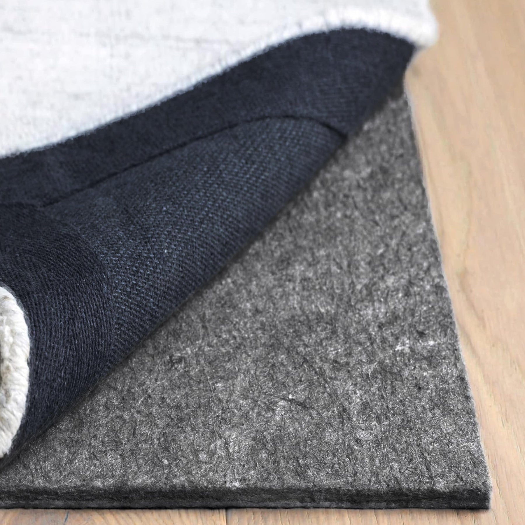 Close-up of a rug with a textured pad on a wooden floor