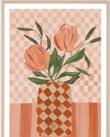 A framed art print featuring a stylized illustration of two peach-orange tulips with green leaves in a checkered terracotta and cream vase, set against a pink and peach checkered background.