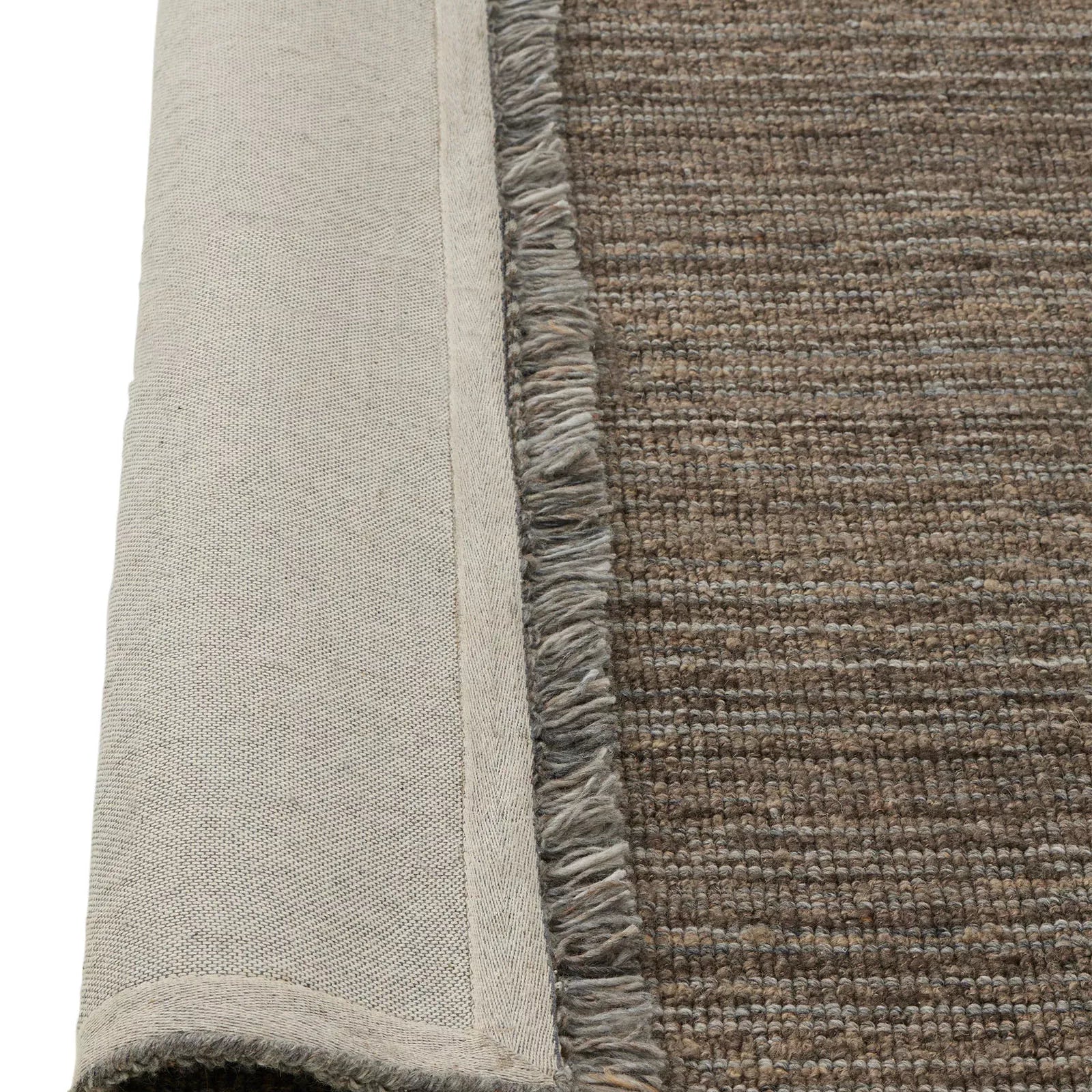 Close-up of a textured rug corner with a neutral color palette.