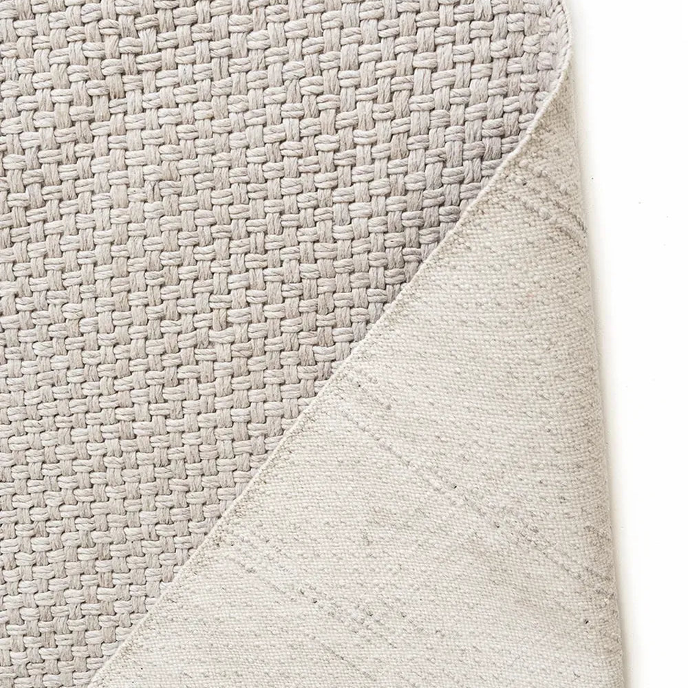 Close-up of a textured gray rug corner on a white background