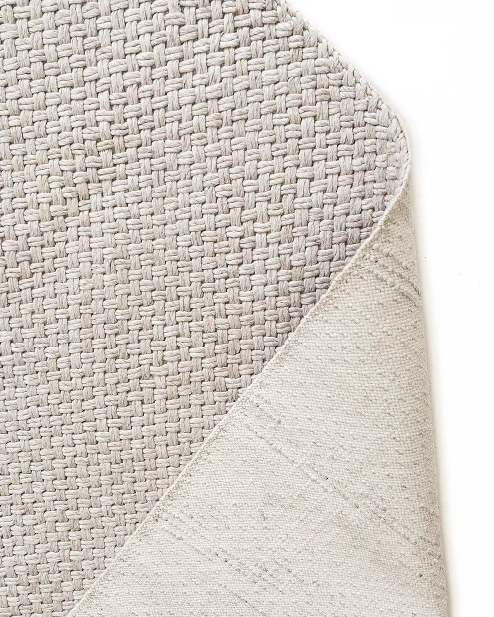 Close-up of a textured gray rug corner on a white background