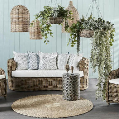 Outdoor furniture set with wicker chairs, sofa, and side table on a wooden deck.