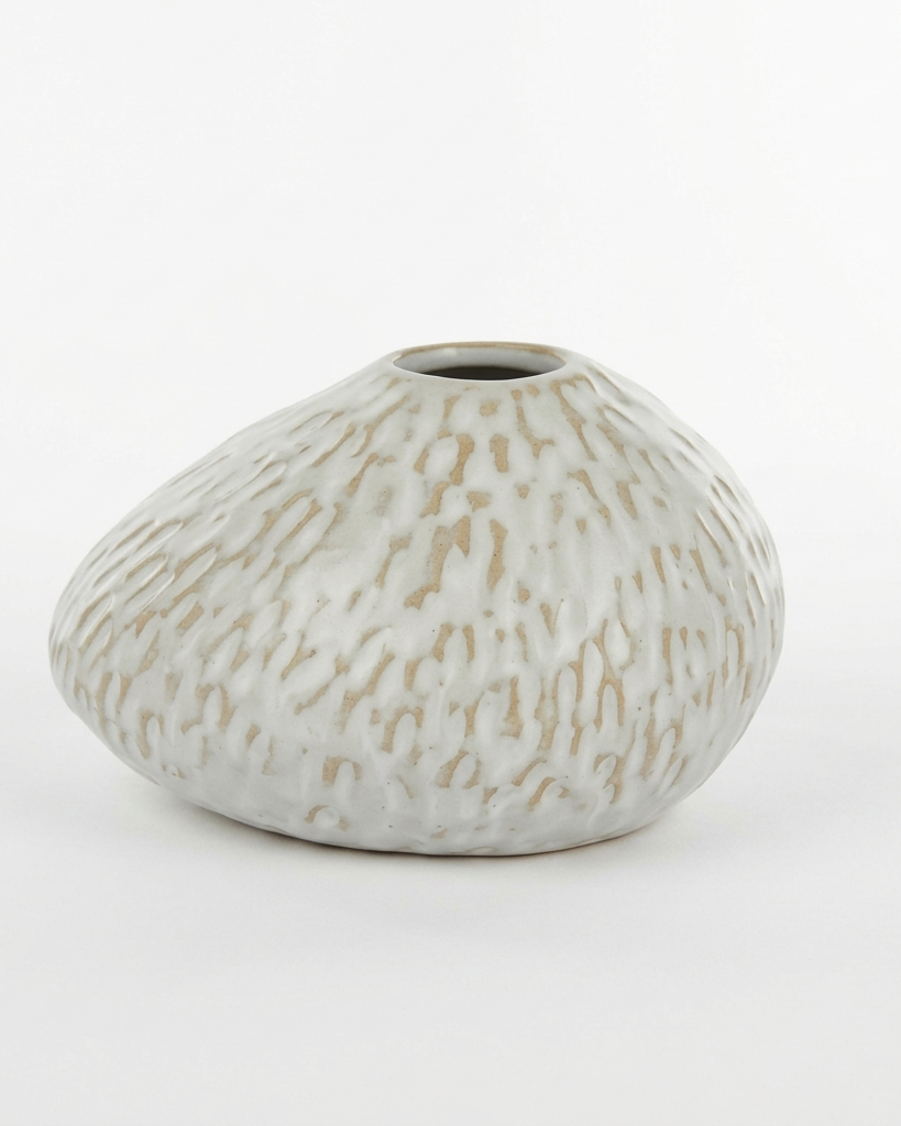 A small organic-shaped ceramic vase with a textured, hand-painted finish in off-white and light brown, set against a plain white background.