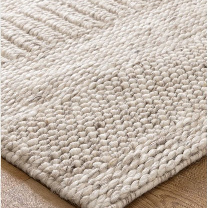 A close-up image of a beige wool and nylon blend rug with a textured pattern.