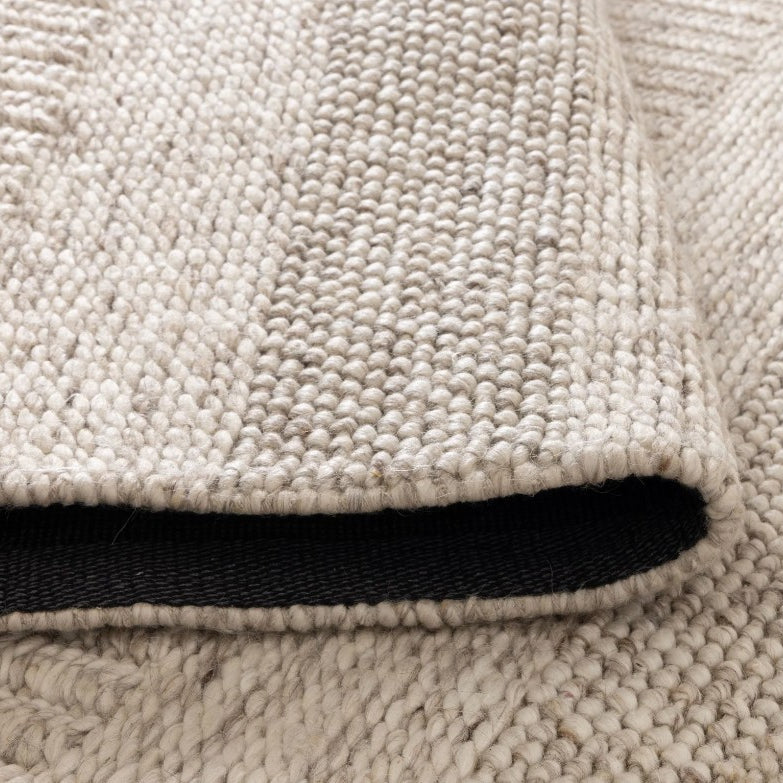 Close-up of a beige textured rug with a black border.