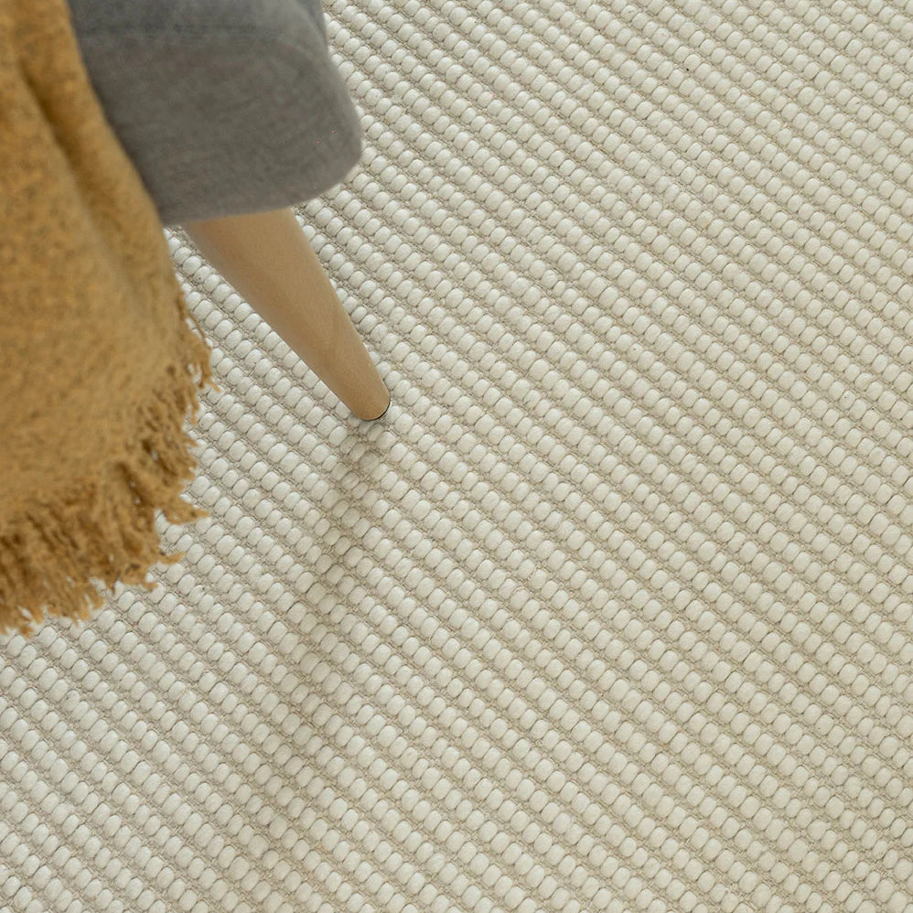 white rug with chair sitting on top and yellow throw