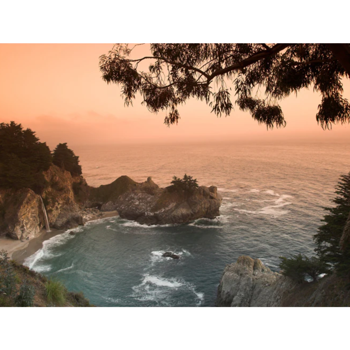 A scenic landscape photograph of a rocky coastal inlet at sunset, with orange sky, blue-green ocean water, dark cliffs, and tree silhouettes framing the top and right edges, shown on a white background.
