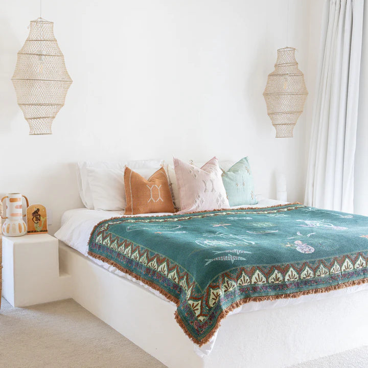 Bedroom with a bed featuring a green patterned blanket and colorful pillows.