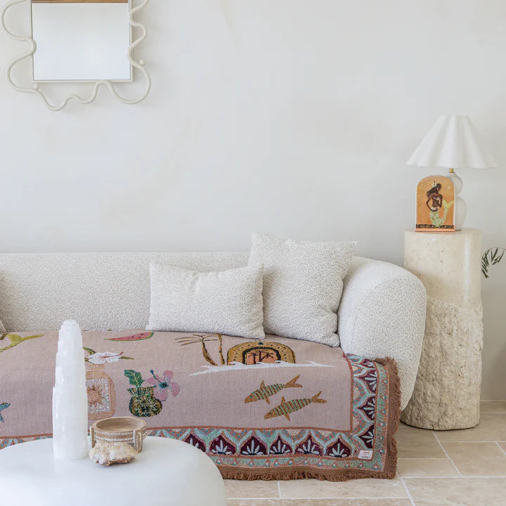 Living room with a white sofa, decorative pillows, and a patterned throw rug.
