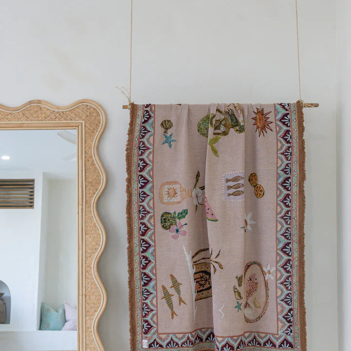 Decorative tapestry with intricate patterns hanging on a wall next to a mirror.