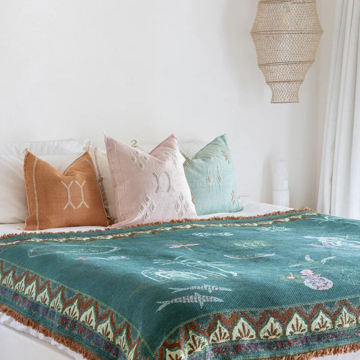 Bed with decorative pillows and a patterned blanket in a bedroom setting.