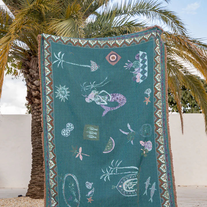 Decorative towel with mermaid design hanging on a palm tree