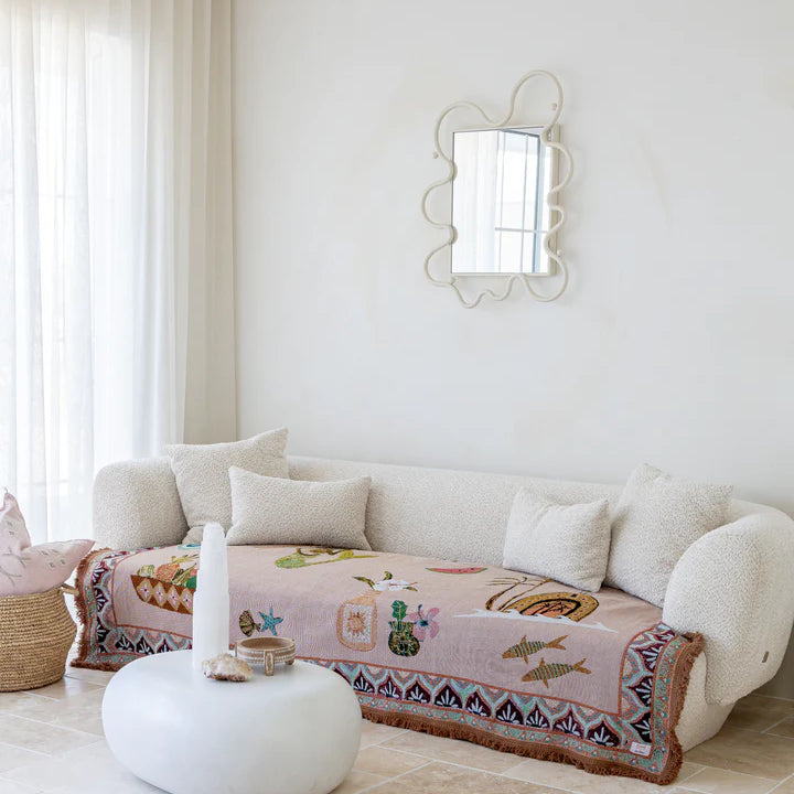 Living room with a white sofa, decorative pillow, and mirror on a white wall.