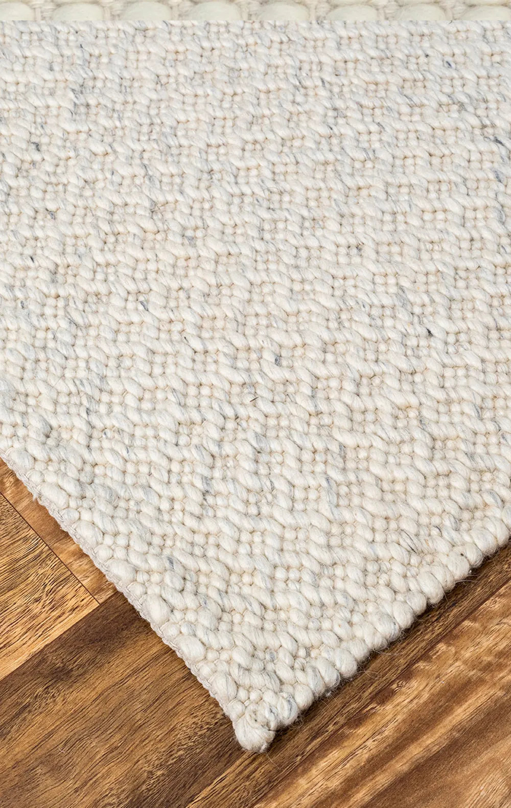 Close-up of a textured white rug on a wooden floor