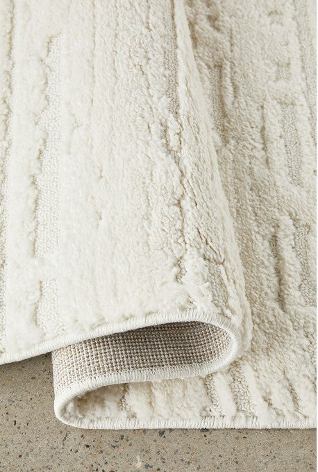 Close-up of a textured beige bath mat on a concrete surface