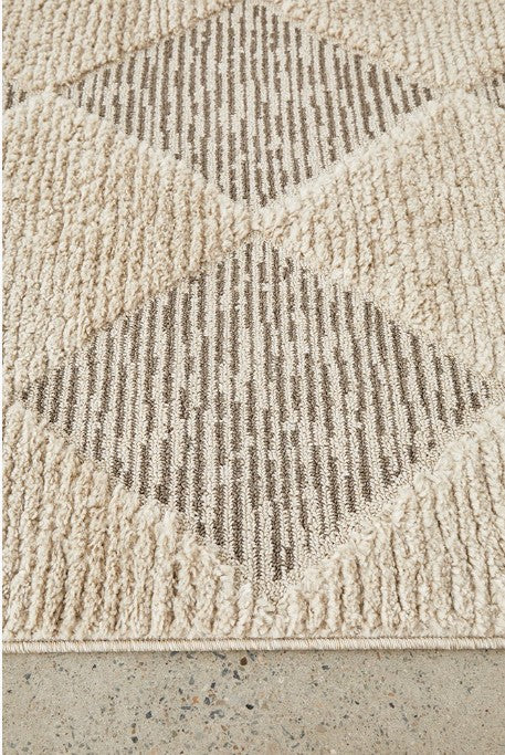 Textured beige rug with geometric pattern on a concrete floor