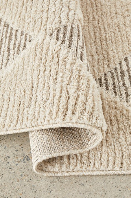 Close-up of a textured beige rug on a concrete floor