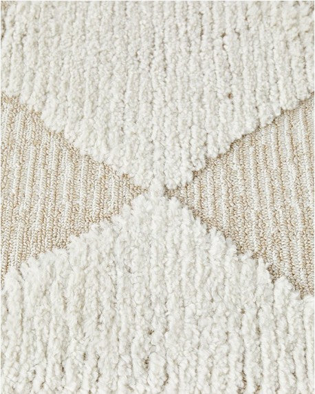 Close-up of a textured beige and white rug with geometric pattern