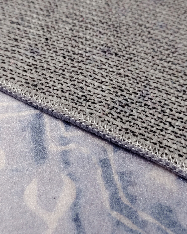Close-up of gray fabric with a textured pattern and visible stitching.