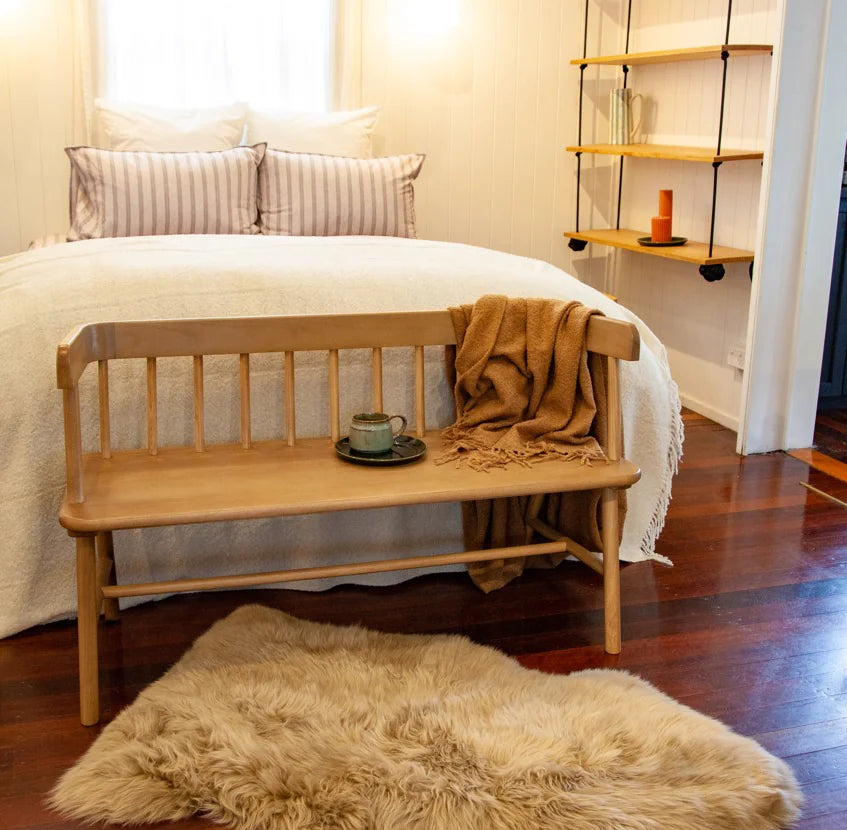 Bedroom with wooden bench, rug, and shelves.