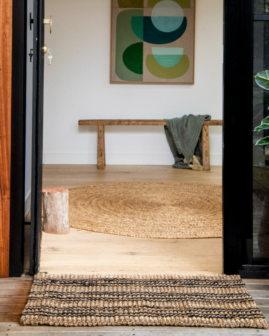 Entryway with woven mat, wooden bench, and abstract art on wall