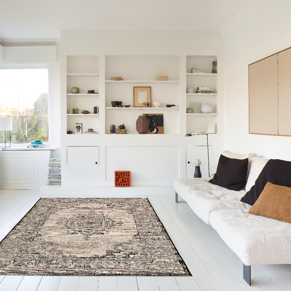 Modern living room with white walls, a rug, and a sofa with pillows.