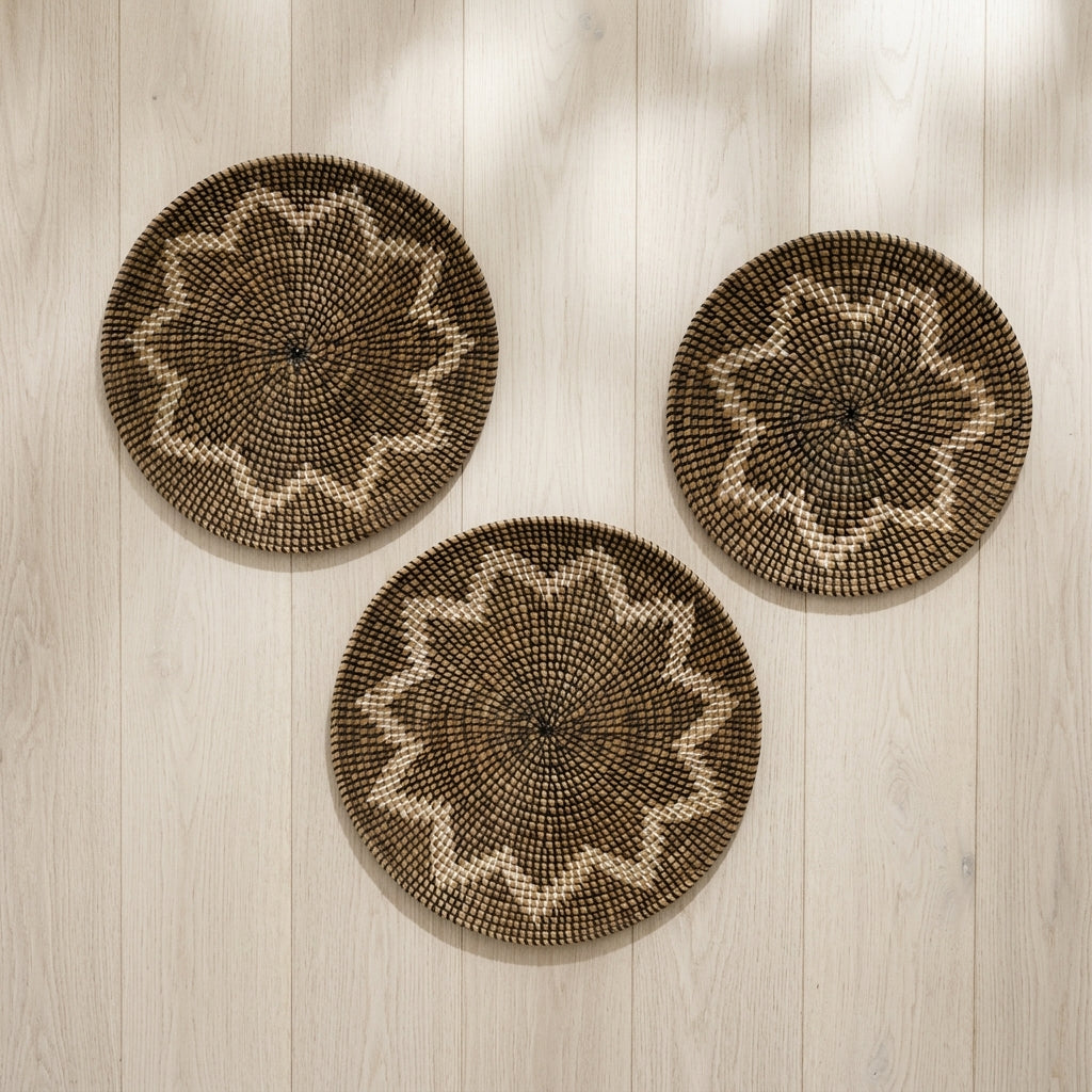 Three round woven wall baskets with starburst patterns in natural brown and beige, arranged on a light wood plank wall.