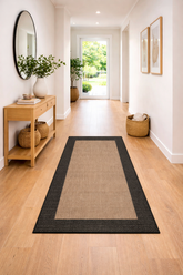 Hallway with a woven rug, wooden console table, and decorative elements.