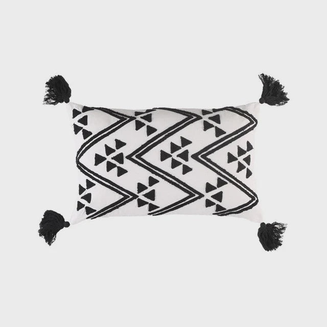 Decorative pillow with black geometric pattern and tassels on a white background